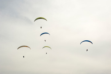 Group of paraglider flying in the blue sky against the background of clouds. Paragliding in the sky on a sunny day.