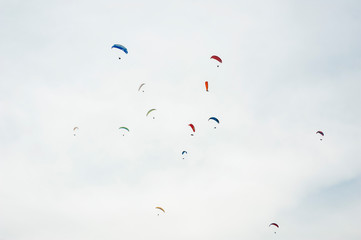 Group of paraglider flying in the blue sky against the background of clouds. Paragliding in the sky on a sunny day.