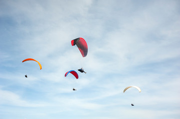 Group of paraglider flying in the blue sky against the background of clouds. Paragliding in the sky...
