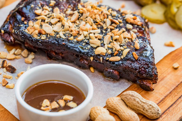 Close up board with pork ribs grilled with BBQ sauce, peanuts and jalapeno