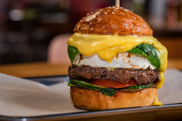 Close up tall tasty burger with cheese served on tray