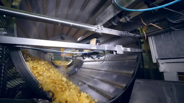 Big machine rotates, adding flavor enhancers to fried potato chips.