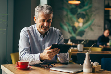 middle aged man using tablet in cafe bar