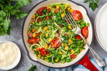 zucchini noodle with tomato, corn and green peas on pan, healthy vegan food