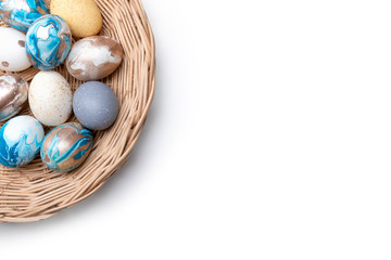 Close up of colorful Easter eggs in the basket on white wooden table background.