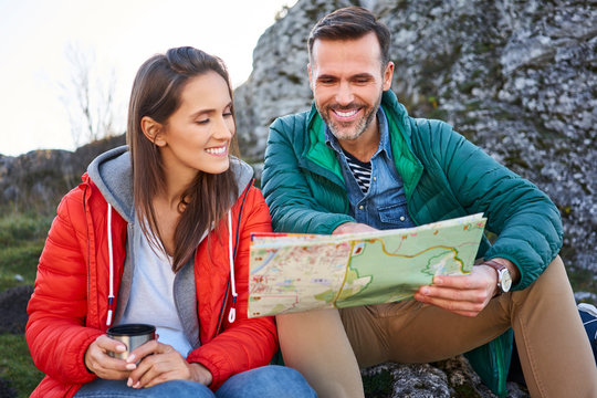 Happy couple on a hiking trip in the mountains taking a break looking at map