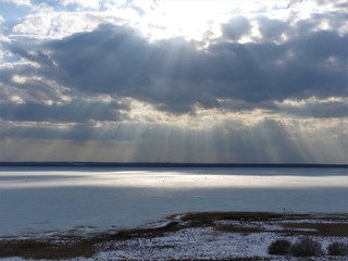 Ice frozen lake on a Sunny winter day in Russia. White snow and clouds in the blue sky. Beautiful winter landscape.