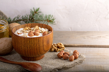 Wooden bowl with whitehomemade yogurt and nuts on burlap on wooden planks. 