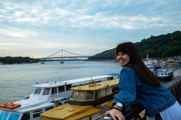Fototapeta premium young pretty woman looking on river at morning time. boats in dock