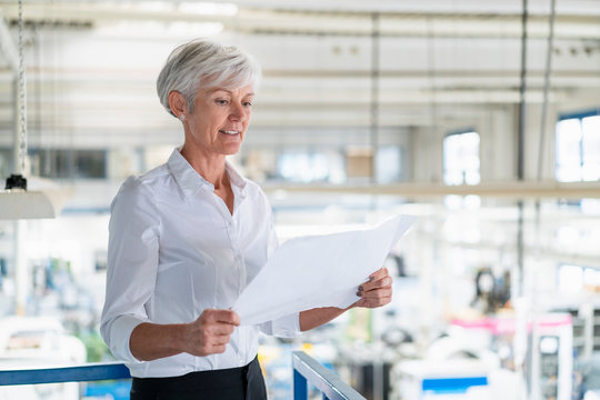 Senior woman looking at plan in a factory