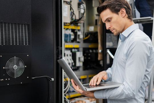Businessman using laptop at a machine in a factory