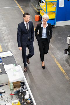 Businessman and senior businesswoman walking in a factory
