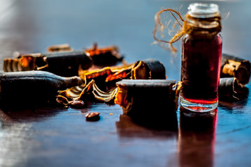 Golden shower tree or garmalo or Amaltas or Cassia fistula oil in a transparent glass bottle along with its fruit and cut pulp on wooden surface.