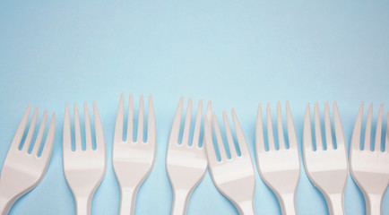 Single-use plastic products: plastic cutlery, cups on bright blue background