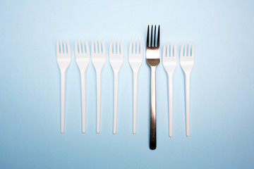 Plastic and metal fork on bright blue background. Creative minimal problems concept