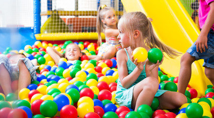 girl playing with multicolored plastic balls .