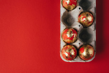Group of painted Easter eggs in cardboard egg-box, Easter egg hunt celebration, colorful still life in paper box on red background.