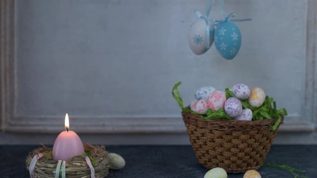 Painted ester eggs in a basket. White vintage wall in background. Copy space.