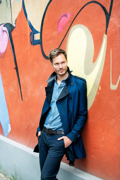 Portrait of a mid adult man, leaning on graffiti wall
