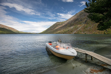 Fototapeta na wymiar Photography of a motorboat with Life Jackets parked at river. landscape of forest and mountains