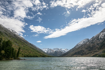 Obraz premium landscape with mountains, green trees and blue lake on a cloudy sky background