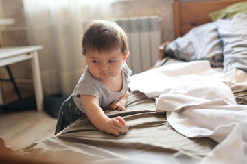 Fototapeta premium the baby is standing by the bed with real interior