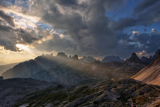 Dreizinnen hut with mountains Tobliner Knoten, Torre dei Scarperi, Croda dei Rondoi, Cima Piatta Alta and dramatic sky with sunbeams. Parco Naturale Tre Cime, Italy
