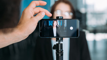 Business presentation in conference hall. Male assistant interviwing young lady, recording video...