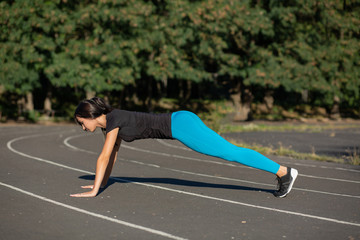 Full length side view of a pretty athletic woman on a plank position