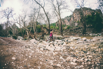 Woman jumps over the mountain river.