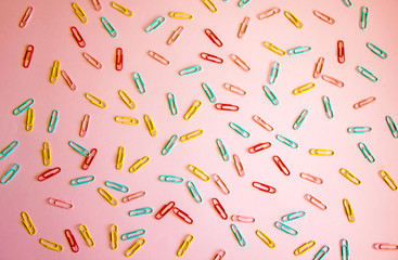 Pink background with colored stationery for paper scattered on it. paper clips on a pink background, office theme. Colorful Back to School background. Top view, flat lay.