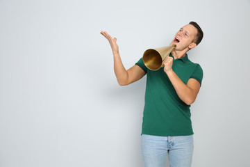 Emotional young man with megaphone on white background. Space for text