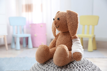 Toy bunny with bandaged pad on pouf indoors, space for text. Children's doctor