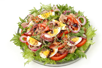 Healthy salad of organic salad with canned tuna, tomatoes, chicken eggs, arugula, red onion and microgreens