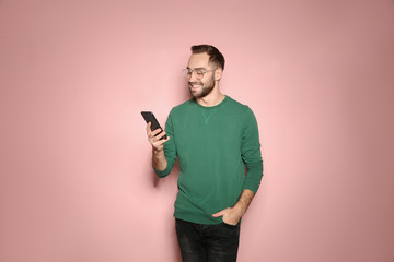 Handsome young man with mobile phone on color background