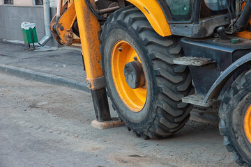 large black and yellow excavator wheels and hydraulic stops close-up on street
