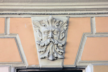 white plant decorative bas-relief with moustached deity men in the form of stucco on the facade of the building