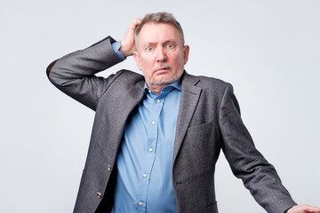 Pensive senior man in suit scratching his head.
