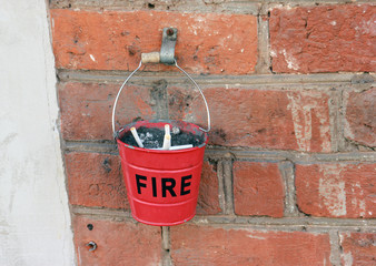 ashtray in the form of a small red fire bucket with the inscription FIRE on the brick wall of the...