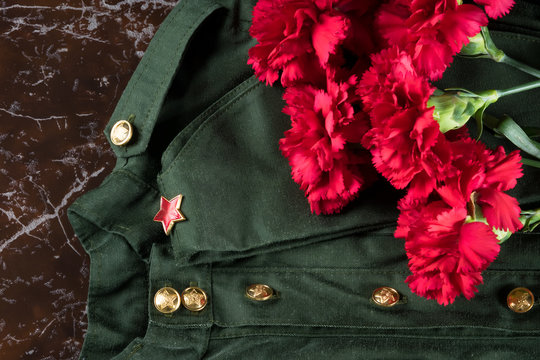 green military uniform and a cap with a red star are on a brown stone