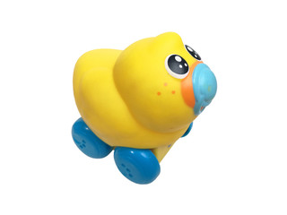 funny children's toy plastic yellow duckling with a nipple on blue wheels with black eyes isolated on white background close-up