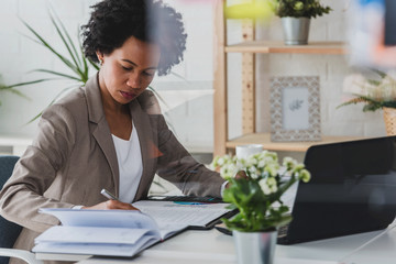 Serious african-american business woman working on laptop at office