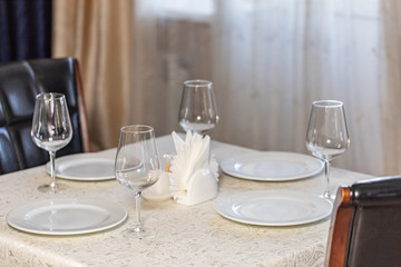 Restourant's table prepared for celebrating event. White tablecloth, leather chairs, transparent glasses