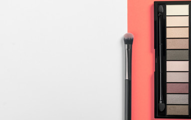 Eye shadow powder palette and brush on coral color background with copy space