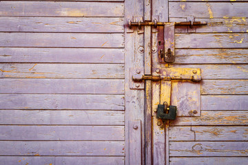 Old lilac color wooden plank door with padlock