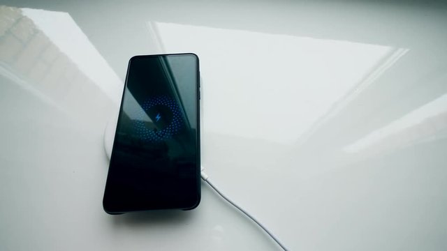One person puts a phone on wireless charger, using wireless technology.