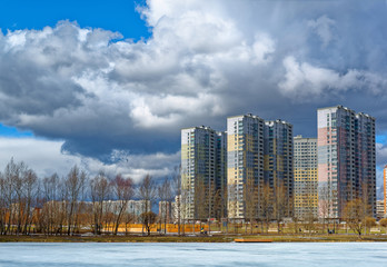 Obraz premium Urban houses and sky with clouds reflected in puddle from melting snow on street in day