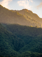 Green mountains with cable cars in the light of the summer sunset. Beautiful sunset in the mountains in summer.