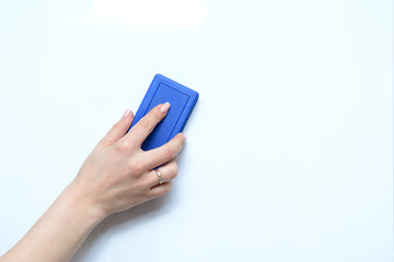 In a female hand a sponge for a school board on a white background. A concept is to start everything from scratch