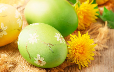 Easter green and yellow painted eggs, yellow dandelion flowers on spring festive composition in rustic style, russian orthodox tradition, vintage wooden background, selective focus